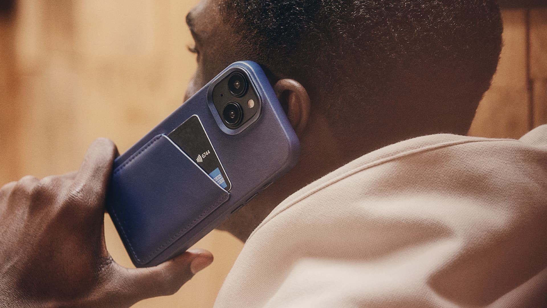 Person holding iPhone 15 Plus in Mujjo's leather case to their ear